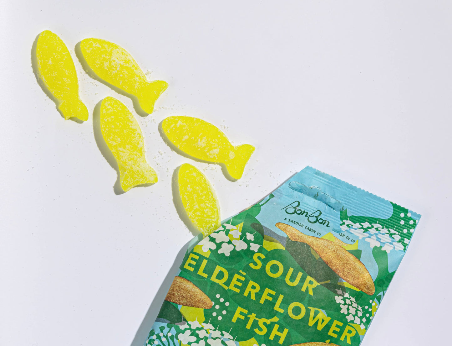 Sour elderflower fish candies with a green packaging on a white background