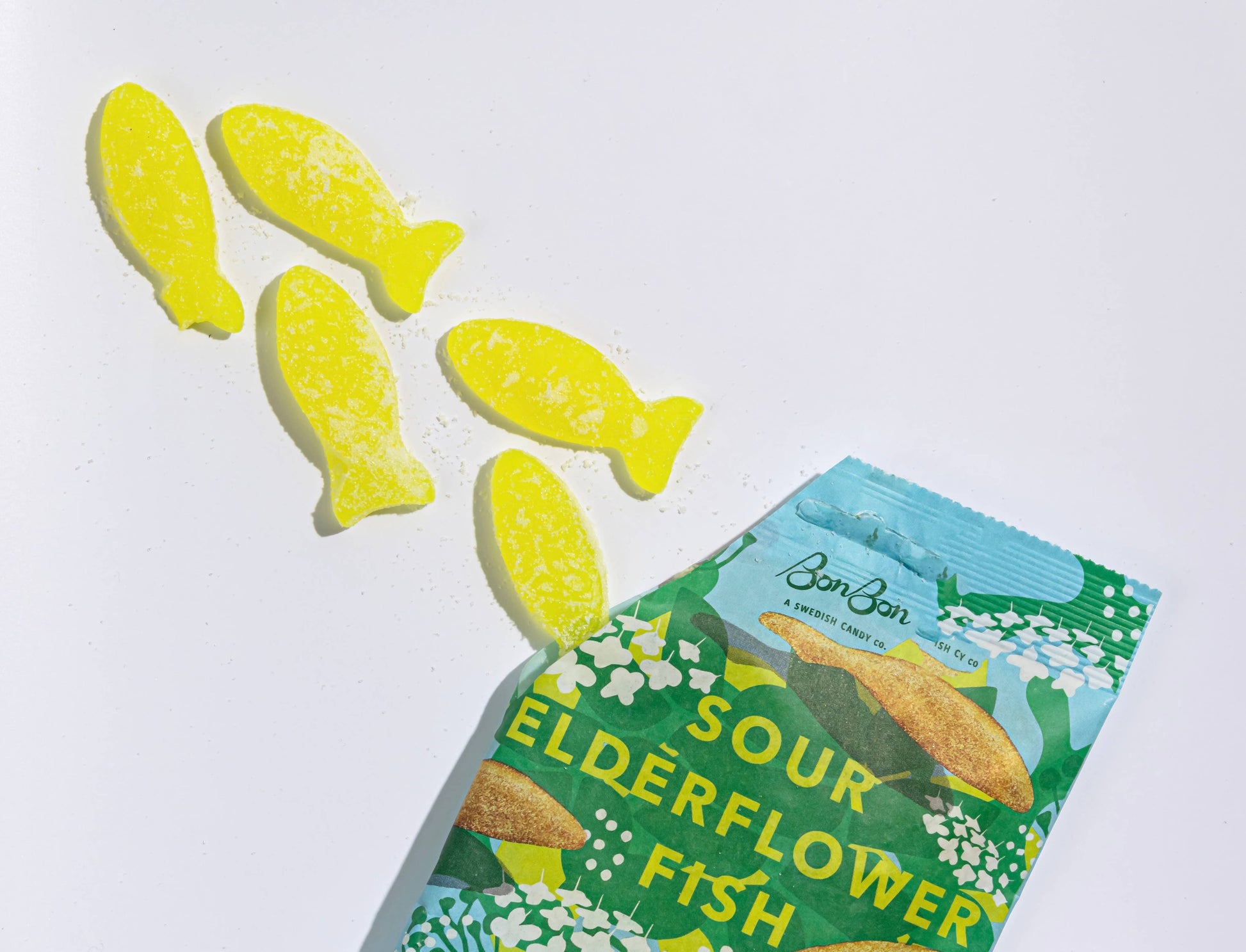 Sour elderflower fish candies with a green packaging on a white background